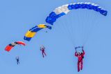 three skydivers flying parachutes together