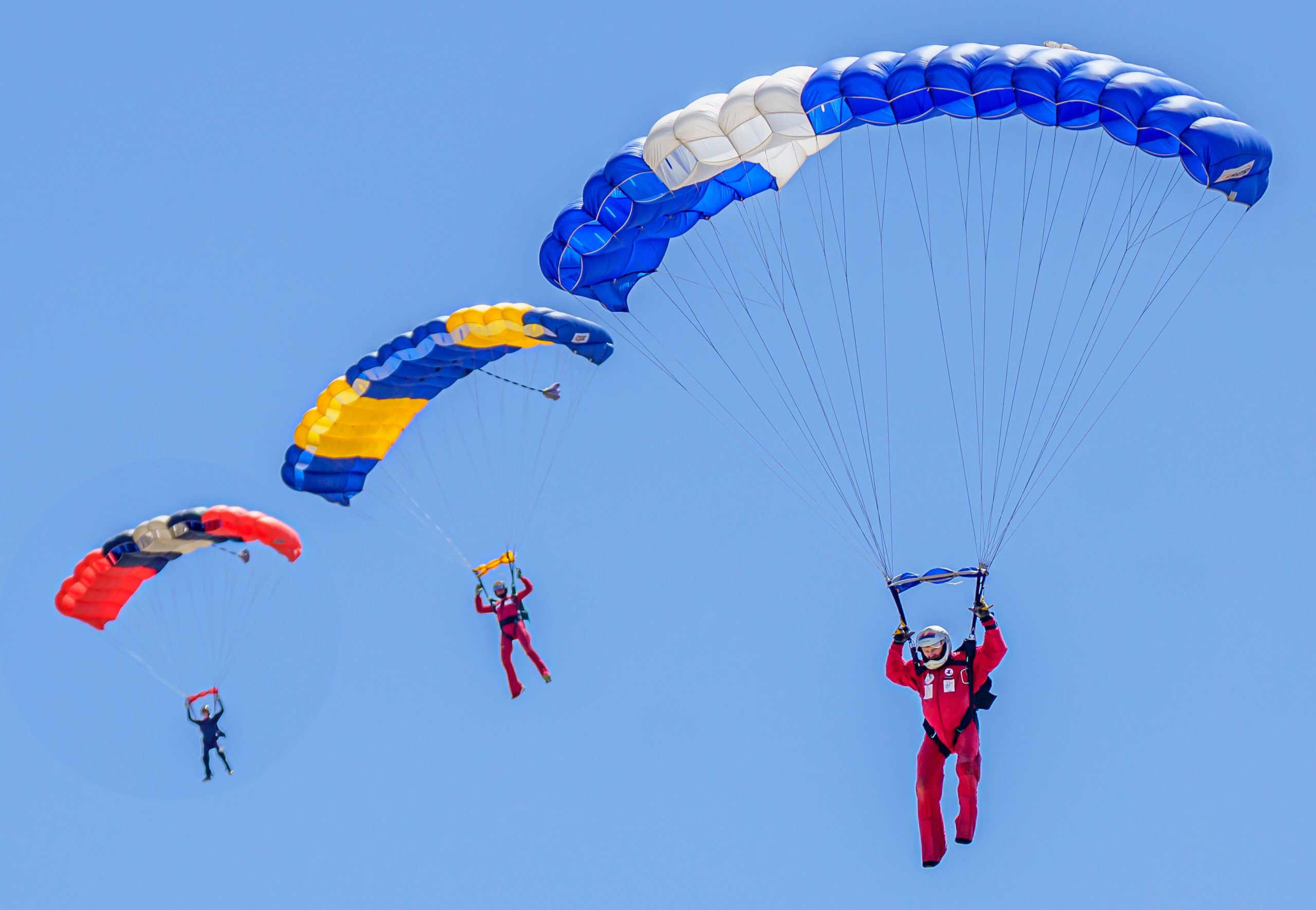 three skydivers flying parachutes together
