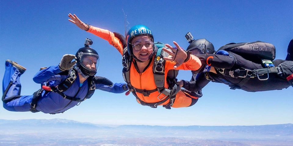 a female student wearing an orange jumpsuit checks her altimeter during freefall