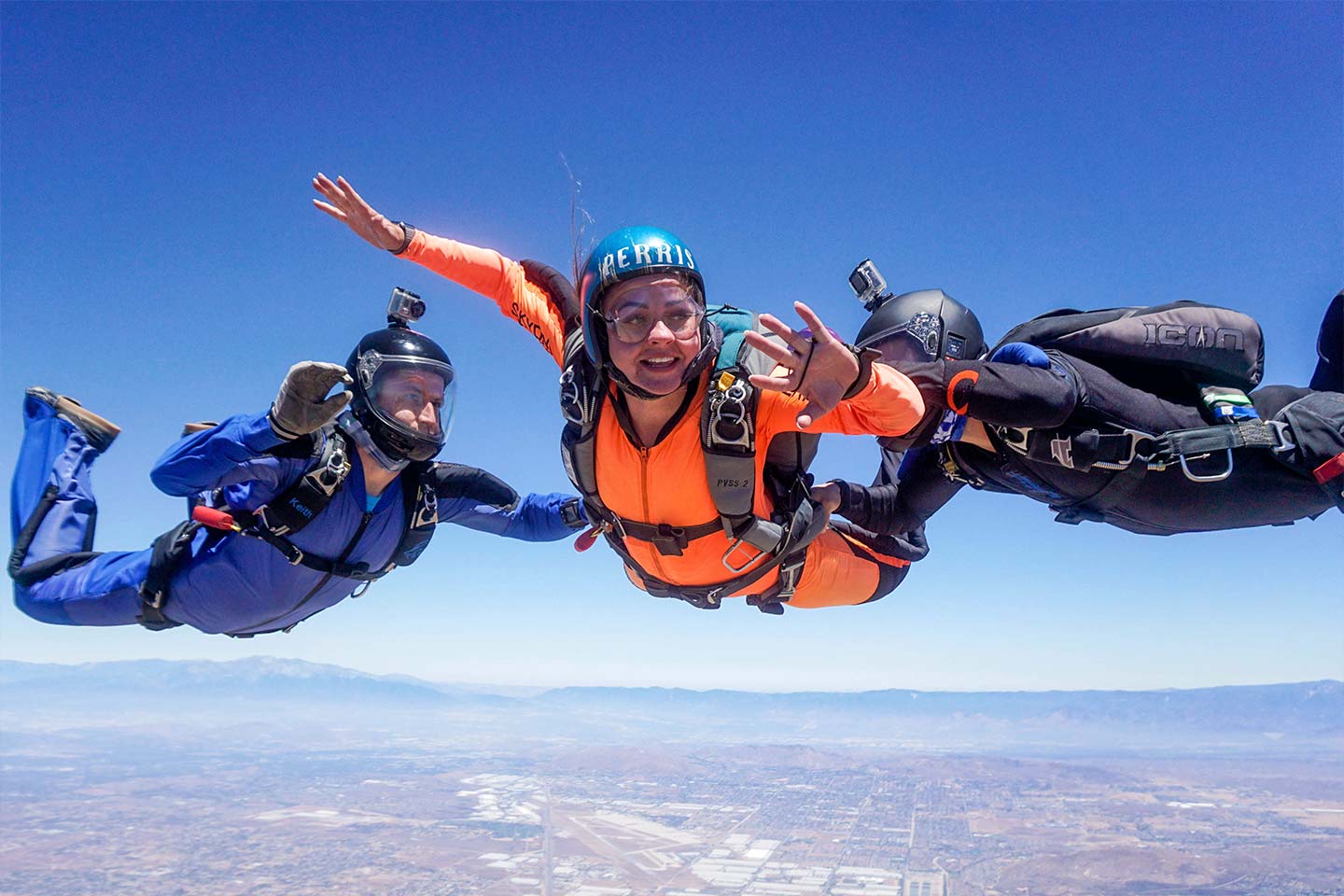 a female student wearing an orange jumpsuit checks her altimeter during freefall