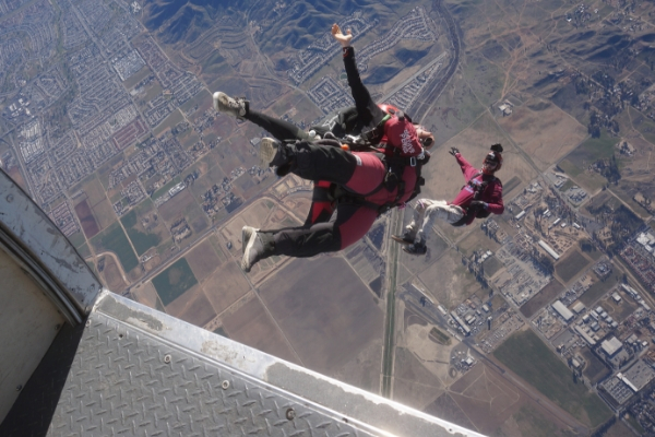 first time skydiver exits aircraft with instructor and camera flyer