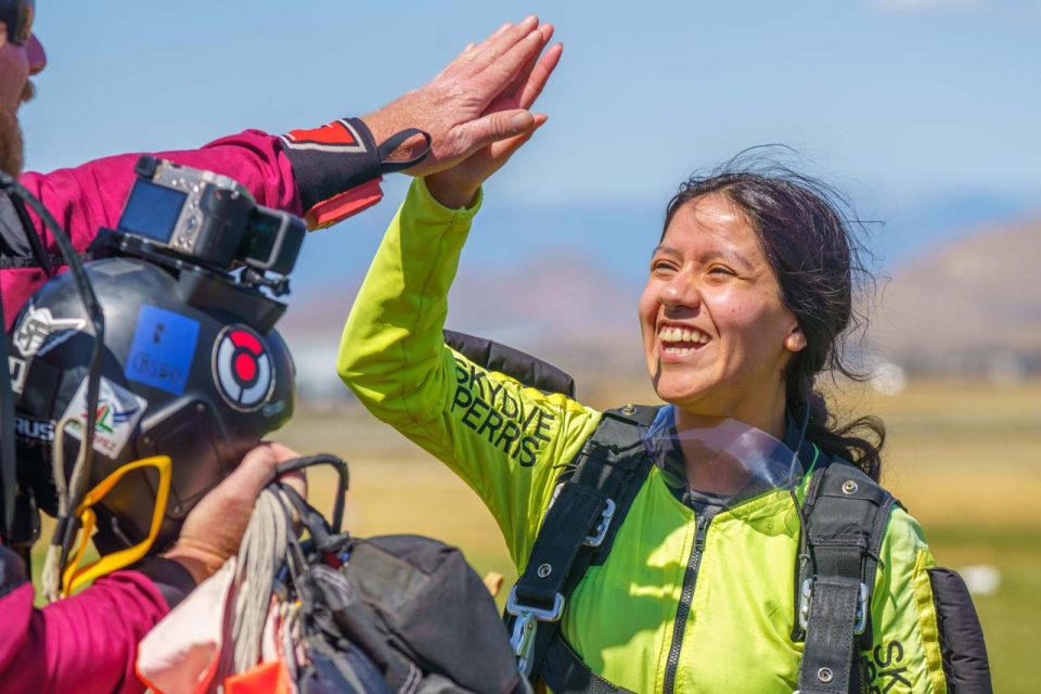tandem skydiving student gives high five after landing