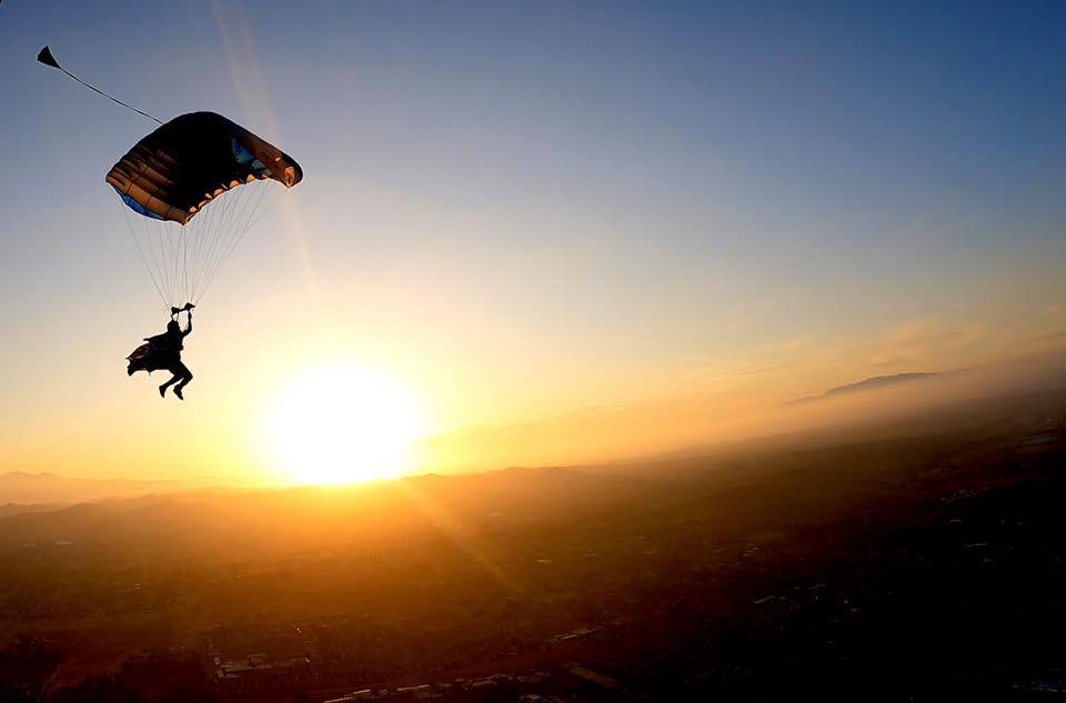 wingsuit skydiver flying their parachute with the sunset in the background