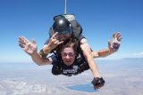 benefits of getting out of your comfort zone tandem skydivers smile in freefall and give the rock on hand symbol